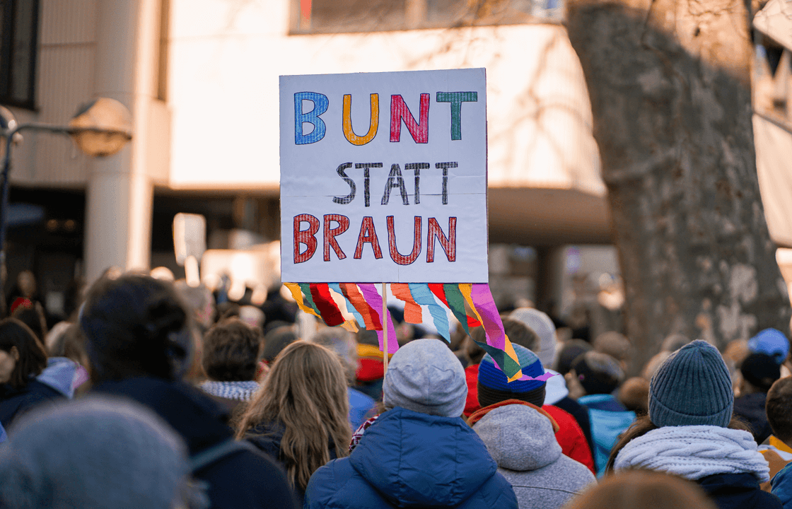 Demonstrierende Menschenmenge und ein Schild mit der Aufschrift "Bunt statt braun"