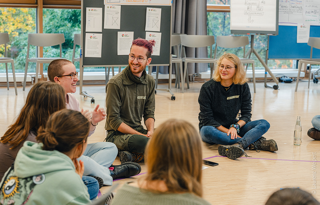 Junge Menschen diskutieren in einem Sitzkreis.
