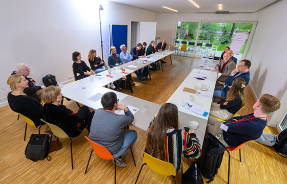 Sitzungsraum mit Teilnehmenden einer Diskussionsrunde.
